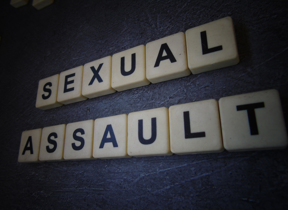 Game tiles spelling “Sexual Assault” on a dark surface, representing Uber sexual assault cases and survivor support from UberHurtMe.com