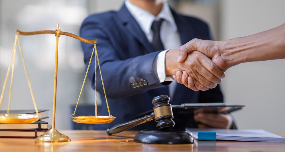 Lawyer for an Uber accident shaking hands with a client at a legal office, symbolizing trust, legal support, and a commitment to fair compensation.