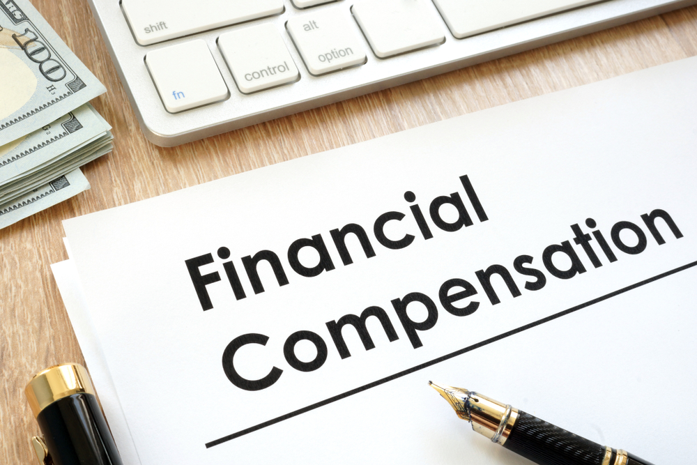Document labeled “Financial Compensation” with money, keyboard, and pen, symbolizing Uber accident compensation for injured passengers in New Jersey.