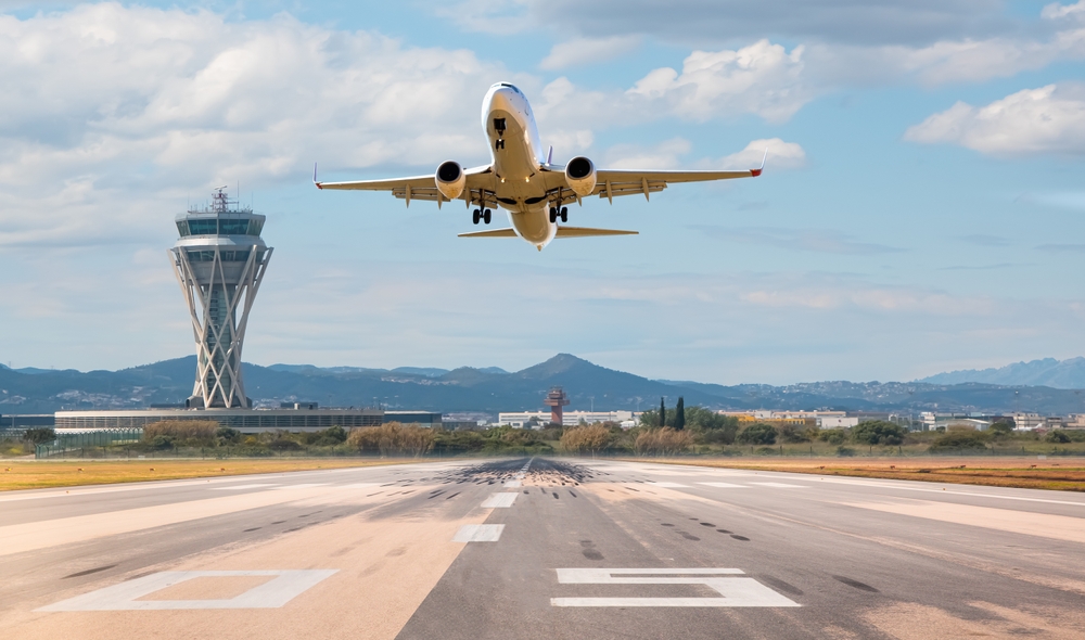 A plane taking off from a runway, symbolizing travel plans disrupted after being injured in an Uber accident on the way to the airport.