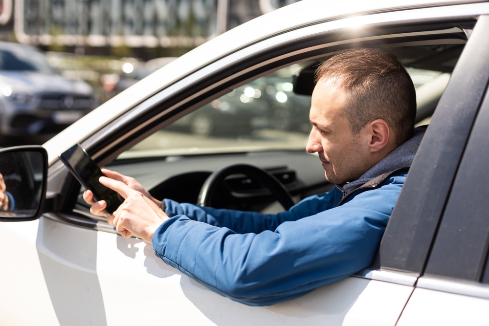 Uber driver holding a phone outside the window during an Uber app malfunction