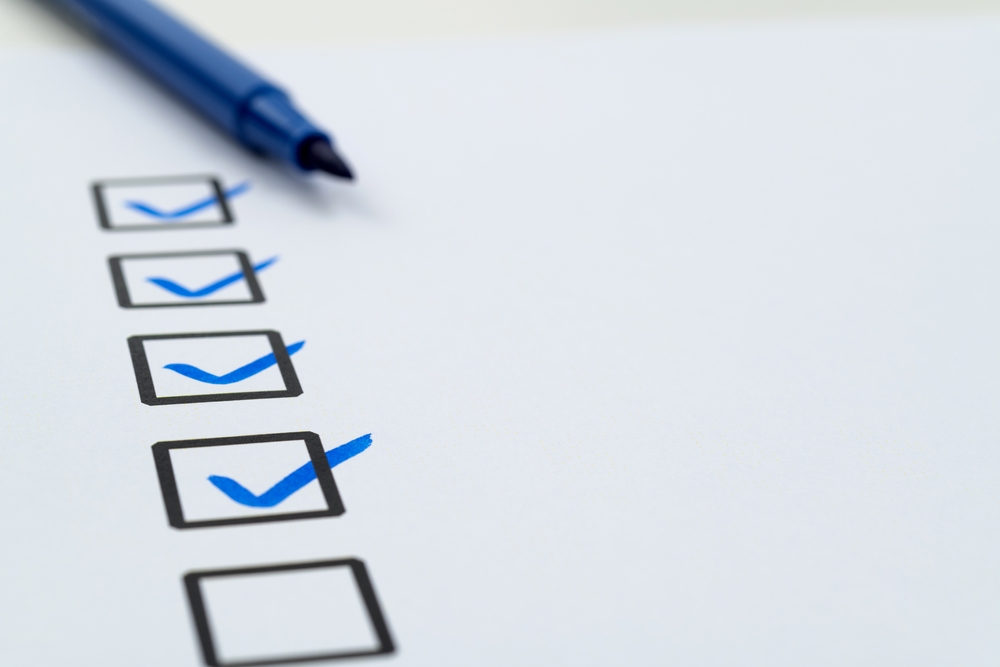 A holiday road trip checklist being completed with a blue marker to ensure vehicle safety and accident prevention.