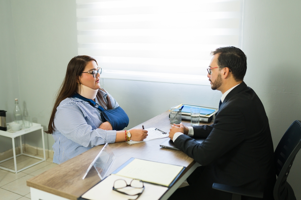 Personal injury lawyer meeting with an injured client wearing an arm sling during a legal consultation in a New Jersey law office