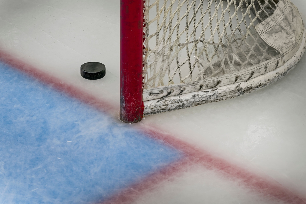 Close-up of a hockey puck beside a red goal post on an ice rink at Westfield Rink following a partial roof collapse after a New Jersey blizzard.