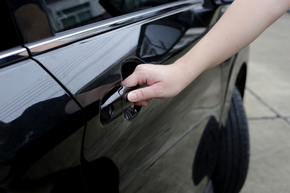 Close-up of a person opening a car door, representing rideshare use and passenger safety concerns