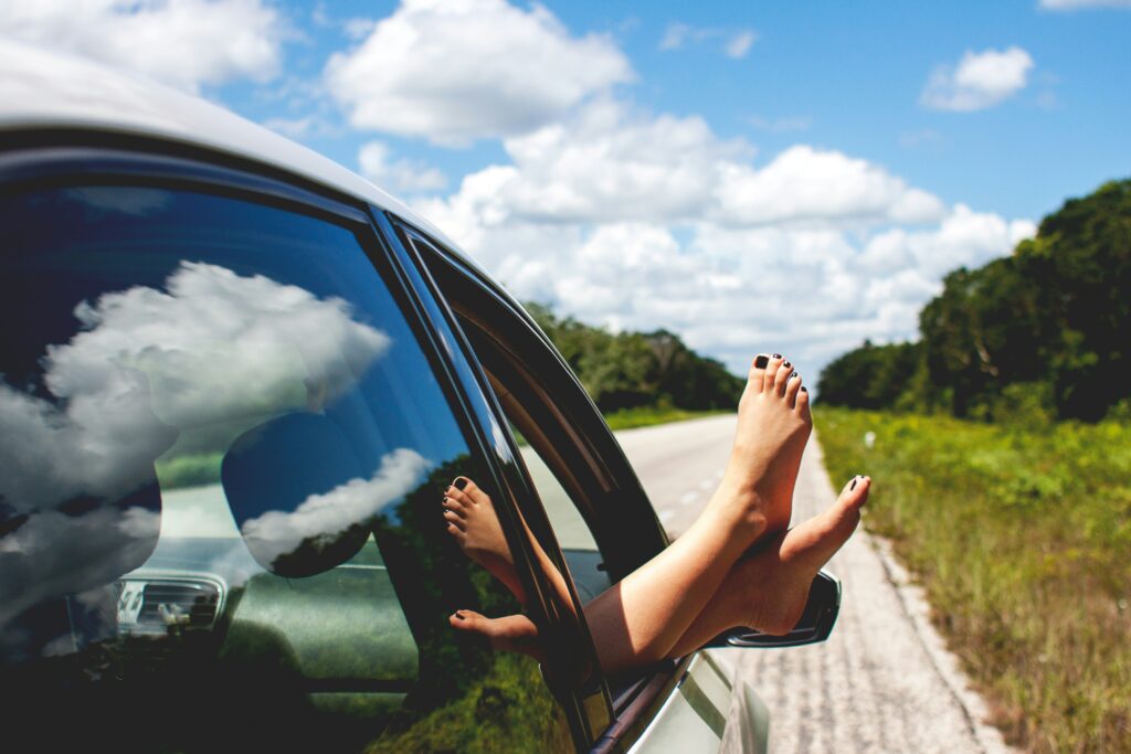 Passenger’s feet out of a car window during a road trip, highlighting the risks of Memorial Day accidents in New Jersey.